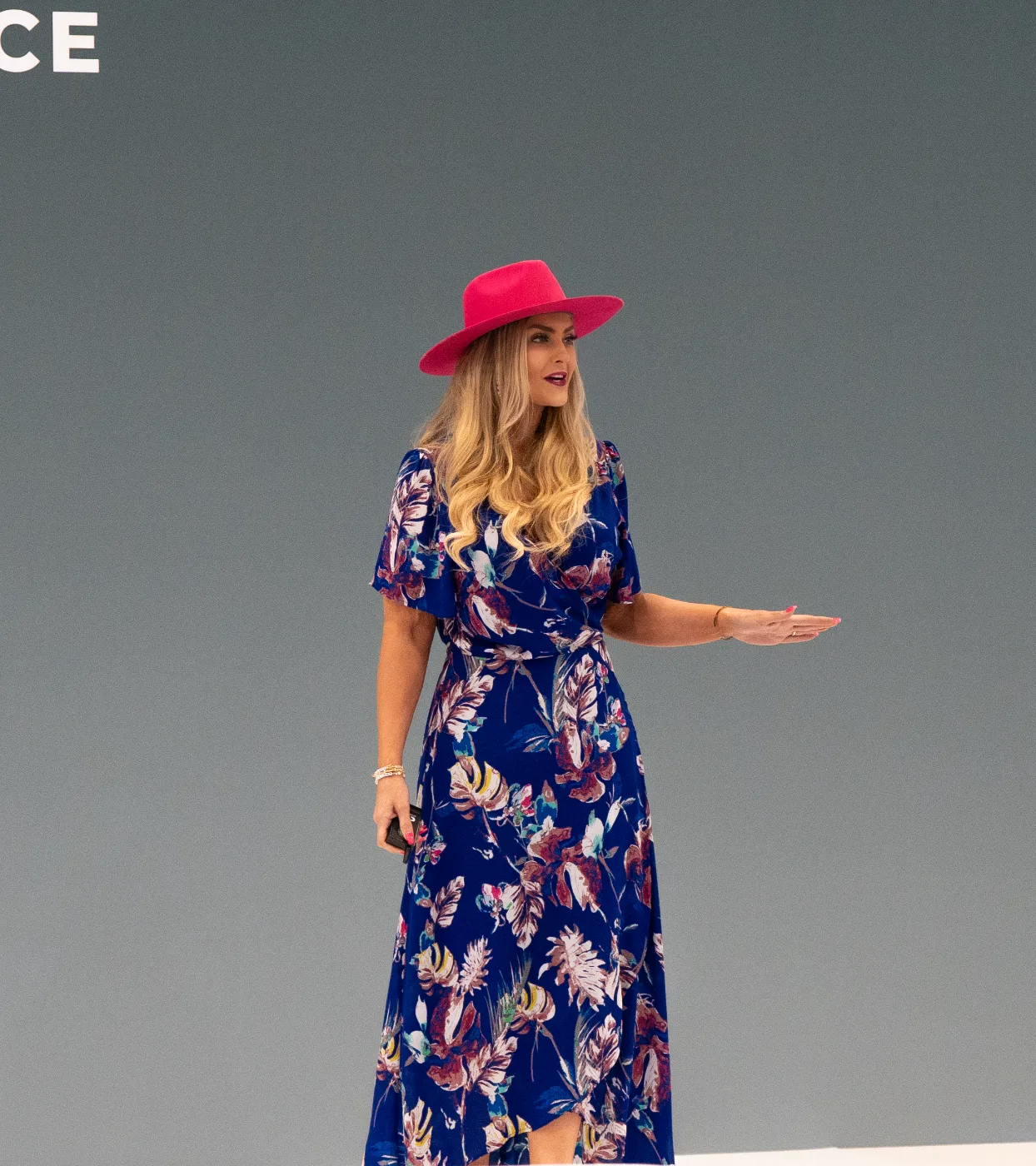 Stefanie Couch on stage in her signature pink hat delivering the Unmistakable in the Age of AI keynote