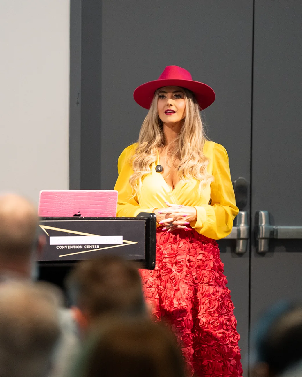 Stefanie Couch delivering a keynote at the Colorado Convention Center in her signature pink hat