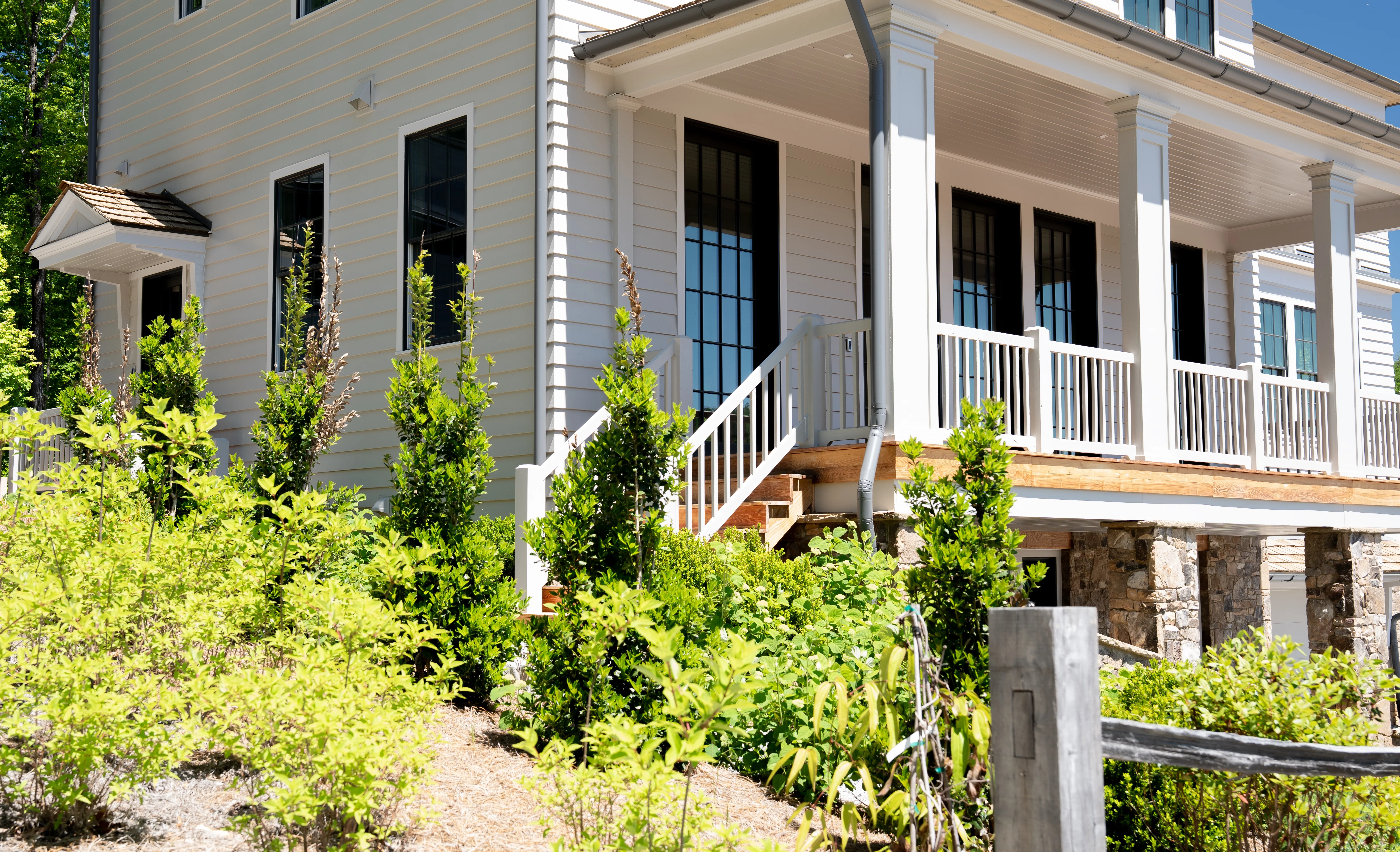 Burton community home with a custom covered roof deck, white railings, and a stacked-stone foundation, designed by Lew Oliver Inc. and built by McKinney Builders, photographed by Grit Blueprint