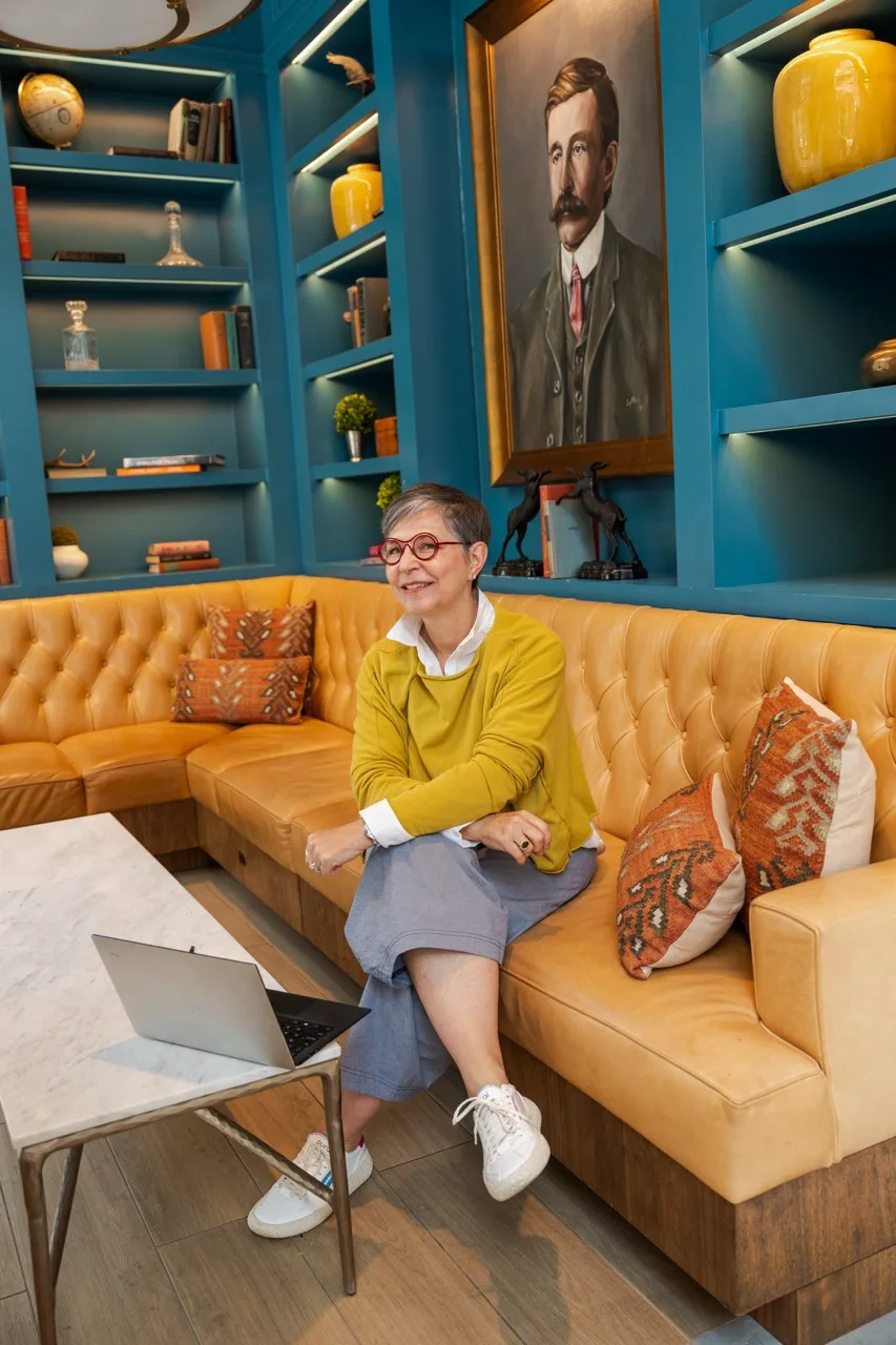 Personal-brand lifestyle portrait of Gina Schaefer in a jewel-toned library lounge, photographed by Grit Blueprint