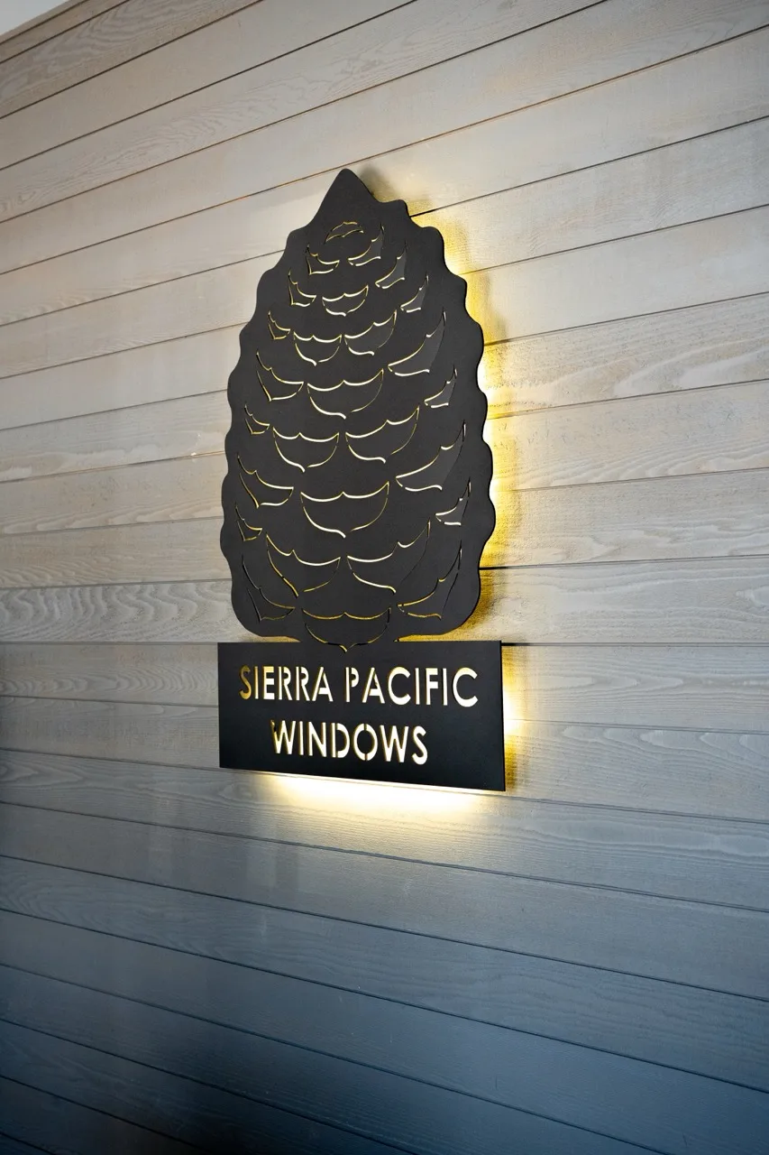 Backlit pinecone Sierra Pacific Windows sign mounted on a wood-clad showroom wall, photographed by Grit Blueprint