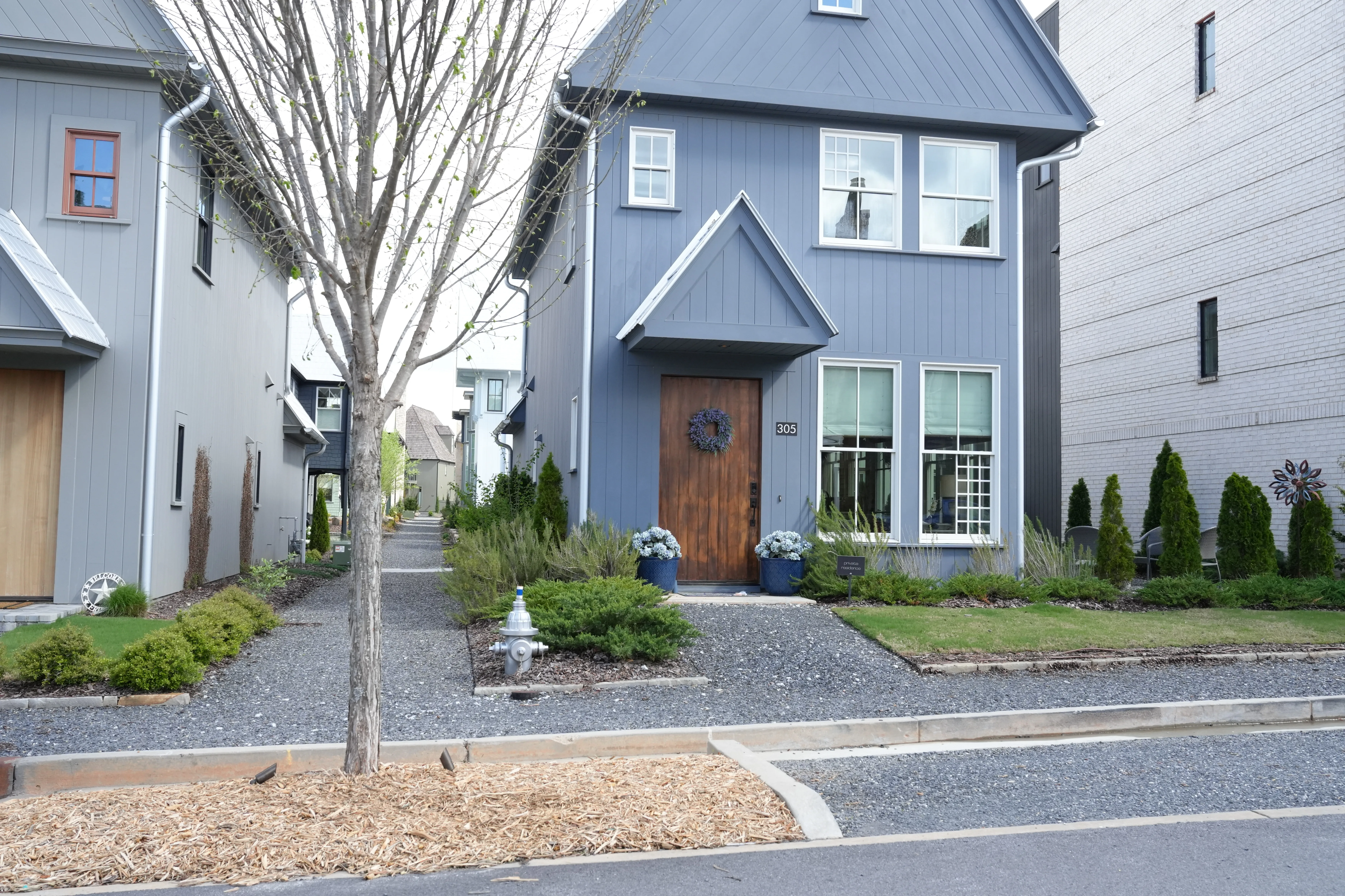 Blue board-and-batten Trilith home with a natural-wood plank door, photographed by Grit Blueprint