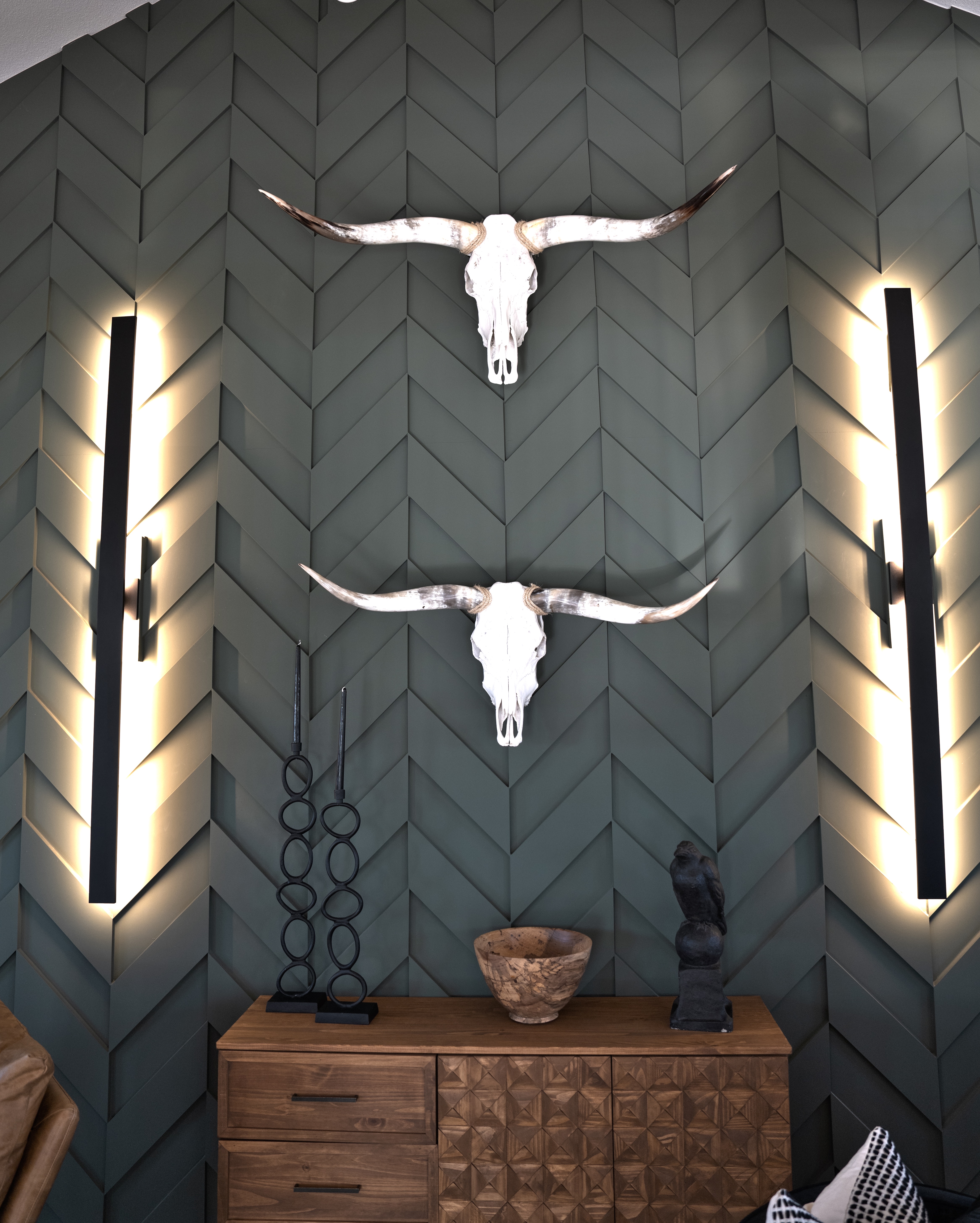 Custom millwork accent wall with chevron paneling and mounted longhorn skulls, photographed by Grit Blueprint