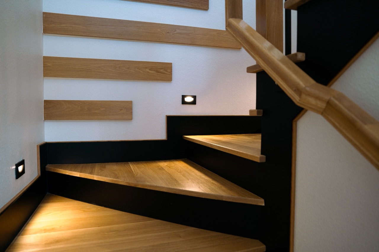 White-oak winder staircase with black risers and recessed wall step-lights, by Coffman Stair Parts, photographed by Grit Blueprint