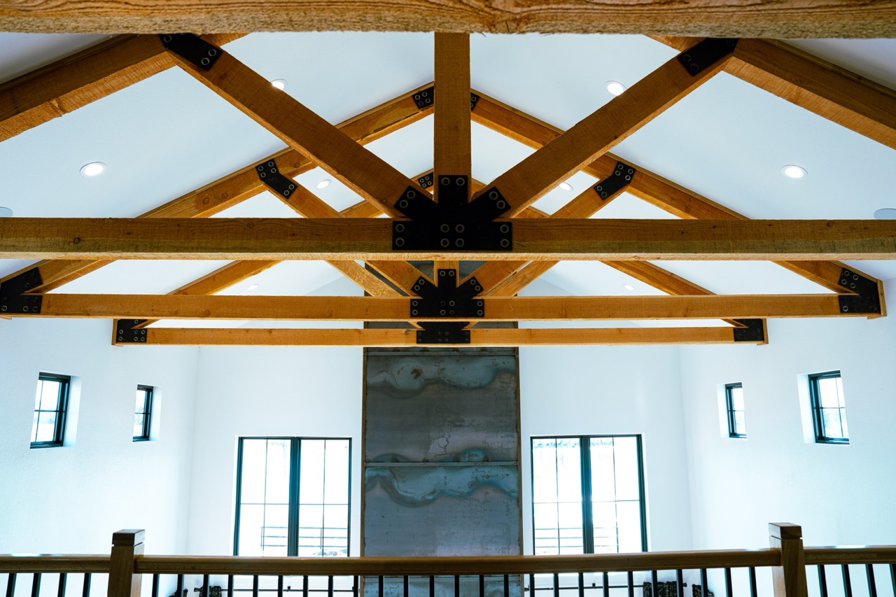 Cathedral ceiling of exposed timber trusses with blackened-steel plate connectors over the great room, photographed by Grit Blueprint