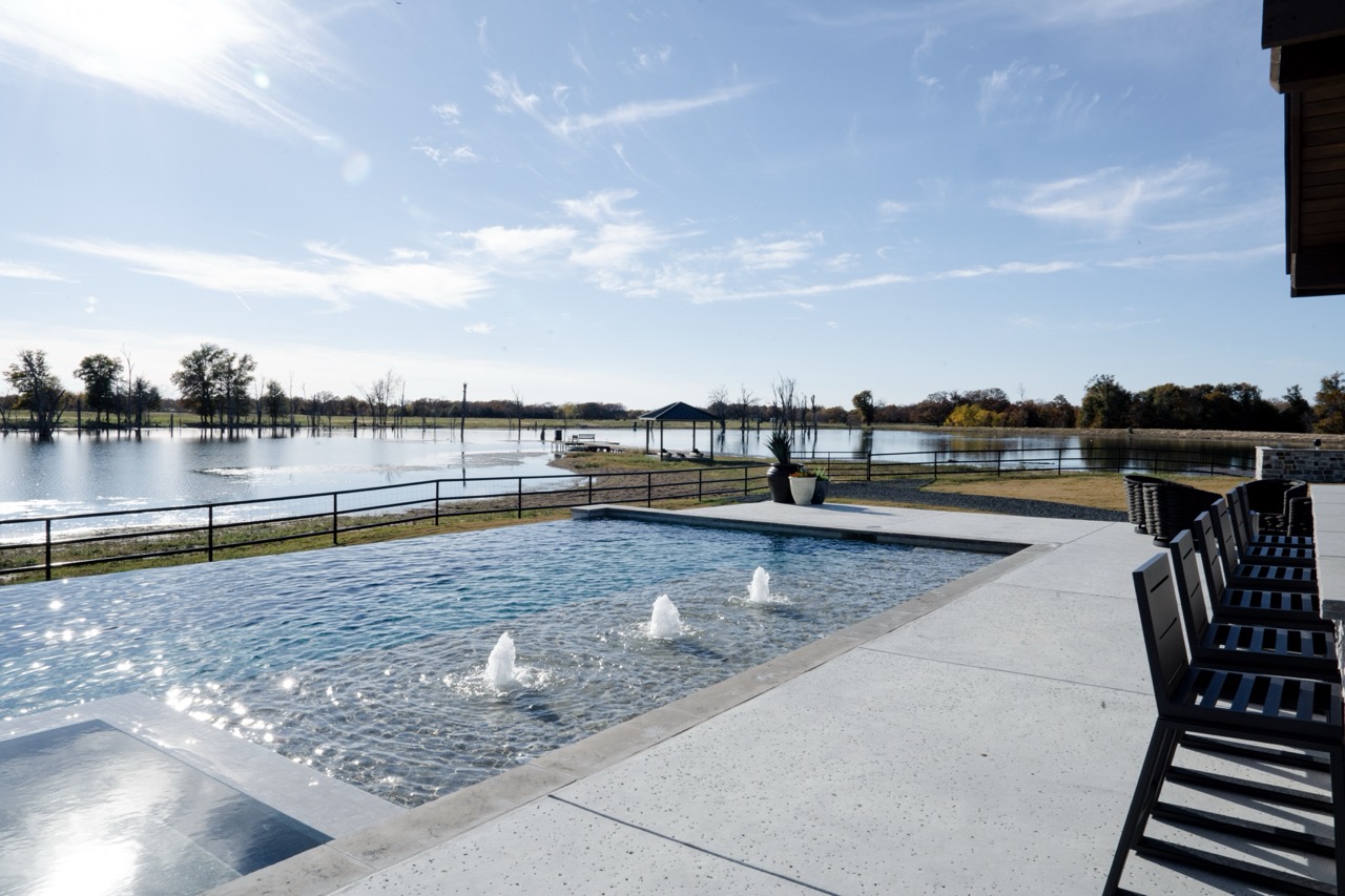 Infinity-edge pool with bubbler jets overlooking the lake at the Harrill Construction property, photographed by Grit Blueprint