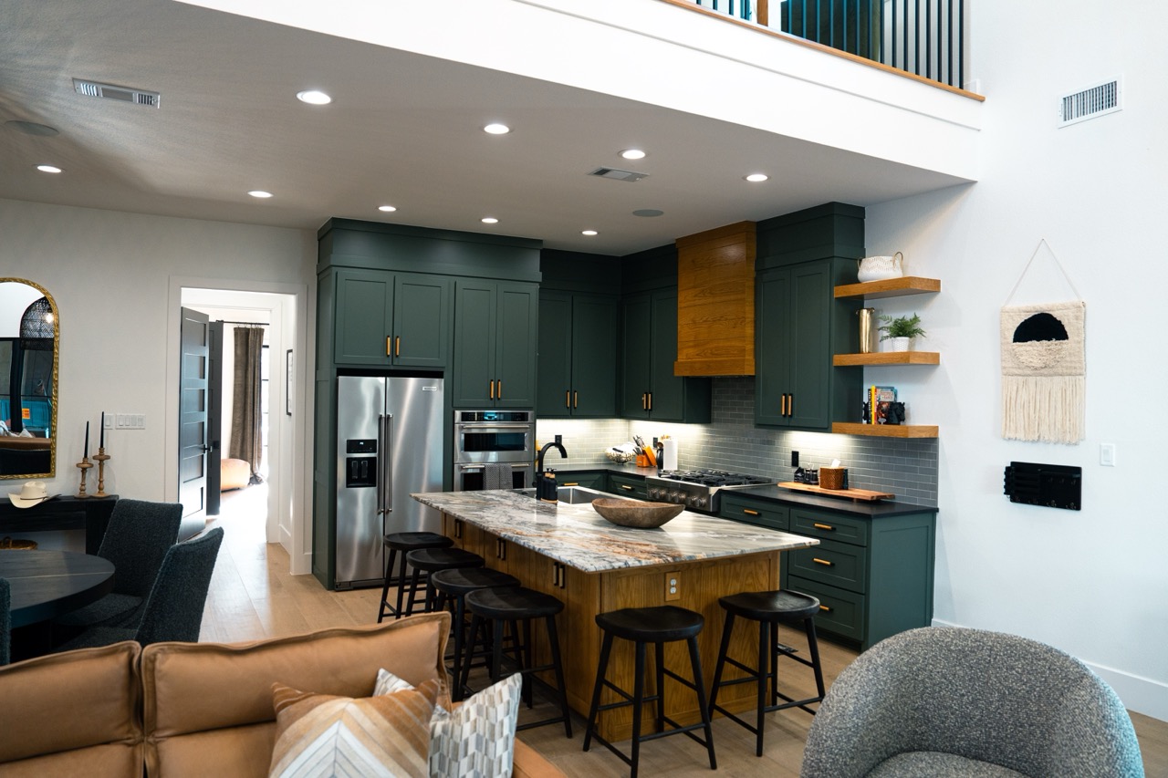 Green-cabinet kitchen and open living space with a marble island and open oak shelves, photographed by Grit Blueprint