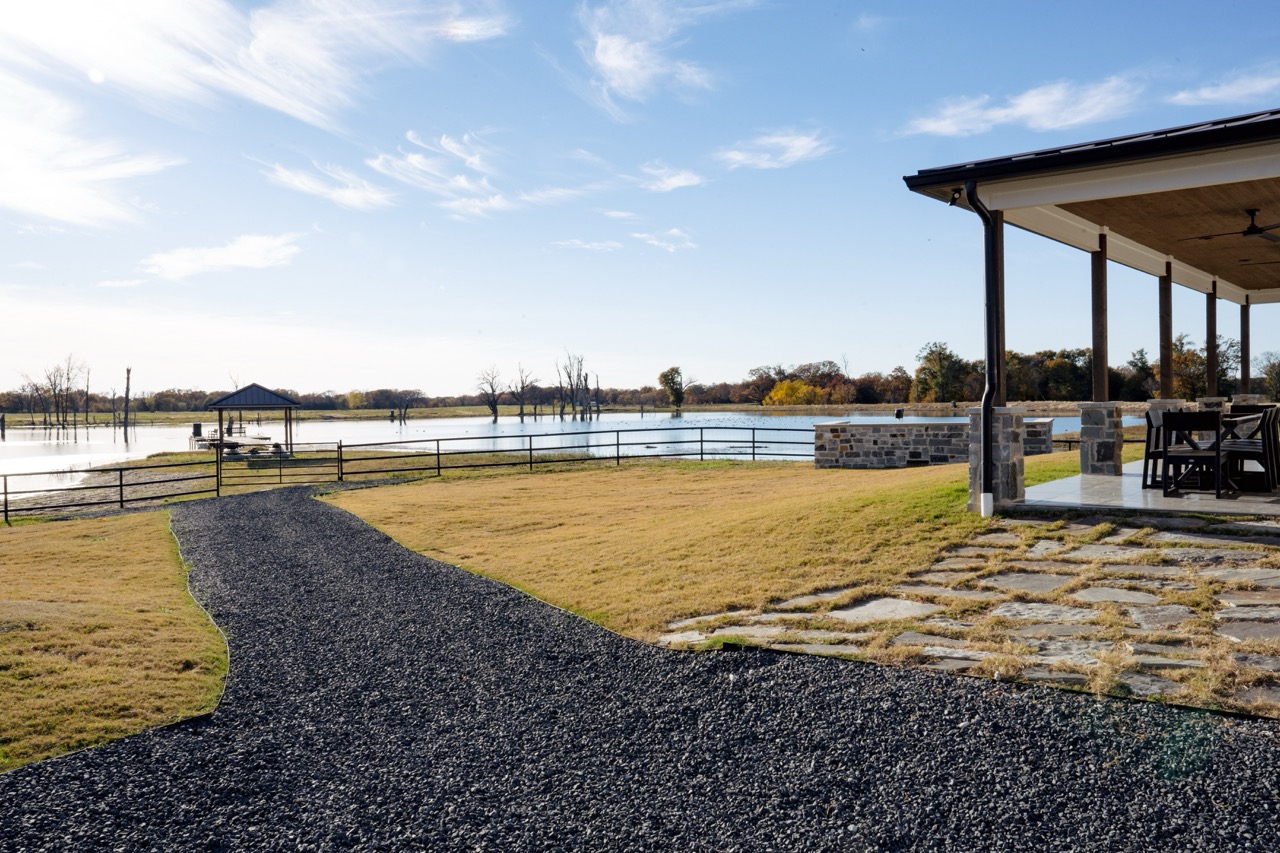 Stone-base lakeside pavilion with a timber roof and the Hanlon ranch crest, photographed by Grit Blueprint