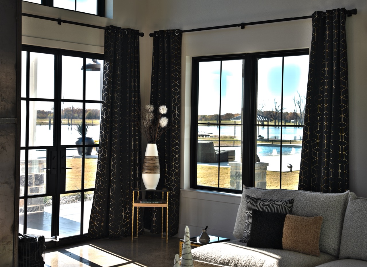 Living-room corner with gold-geometric drapery framing floor-to-ceiling windows over the lake, photographed by Grit Blueprint