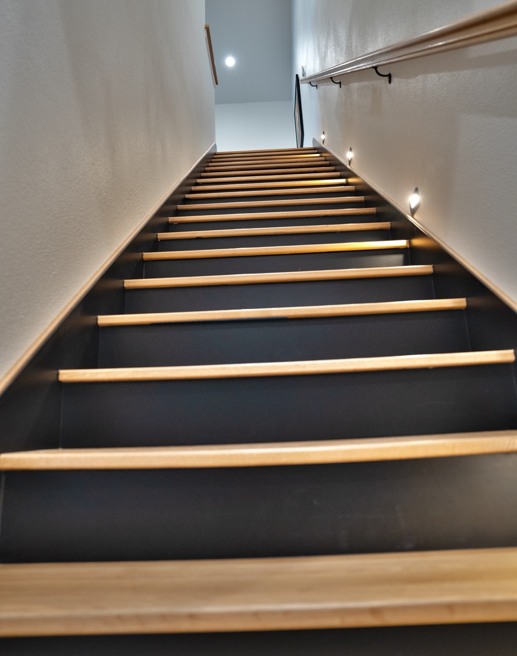 Straight-on view up a white-oak stair with lit treads and wall-mounted step-lights, by Coffman Stair Parts, photographed by Grit Blueprint