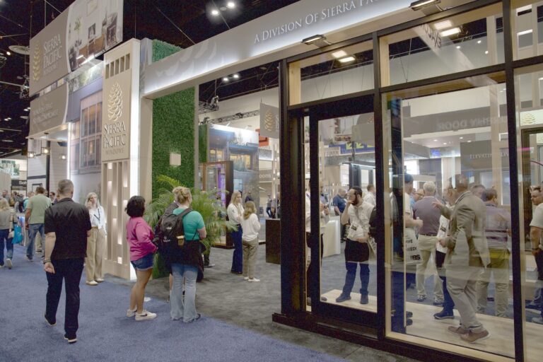 People walking past large glass doors at the front of the Sierra Pacific Windows booth