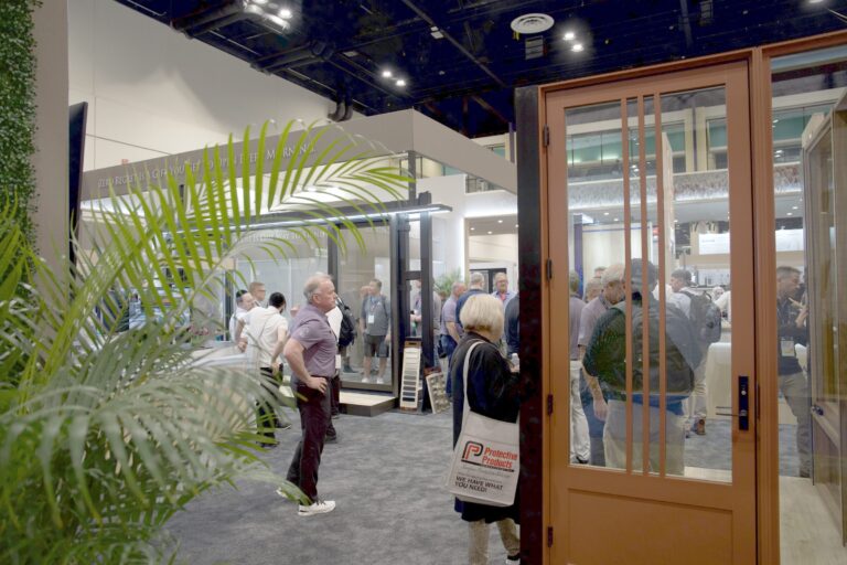 A wood-framed glass door display beside a palm, with people in the booth behind