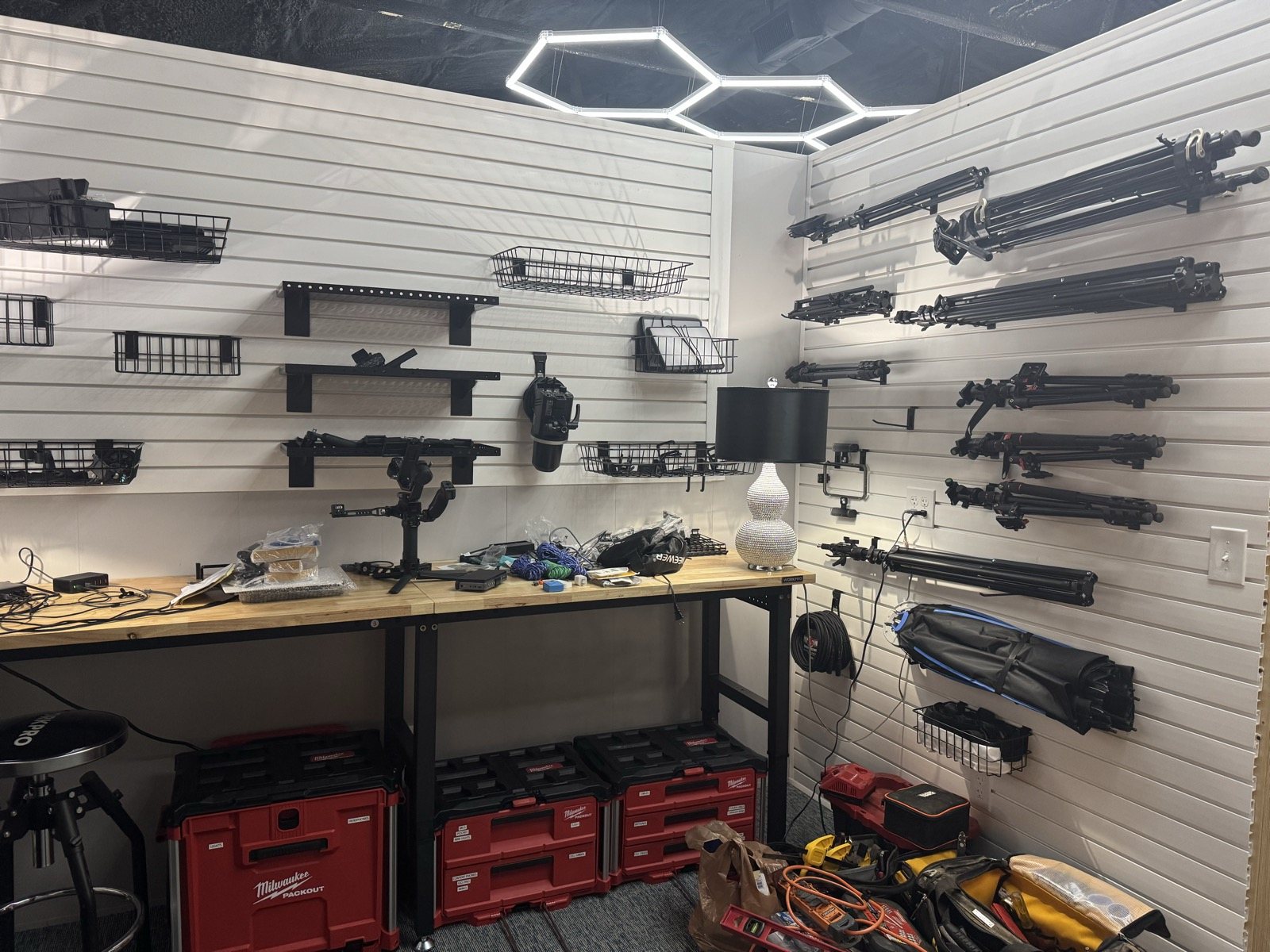 Tripods and light stands hanging on a Trusscore slat wall in a corner of the Grit Garage