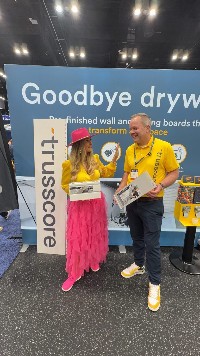 Stefanie Couch and Joel Koops of Trusscore holding product samples in front of a Goodbye drywall banner at IBS 2026
